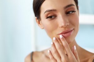 Woman touching her face after facial fat grafting in Mount Vernon, WA